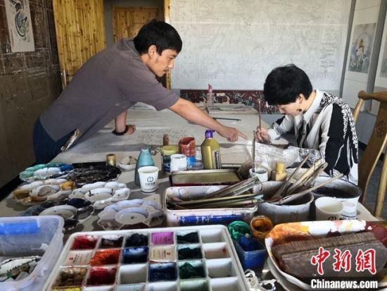 圖為2020年8月下旬，敦煌“80后”畫家張杰龍(左)在為云南麗江“學(xué)生”莫北講解敦煌壁畫的繪畫技巧?！●T志軍 攝