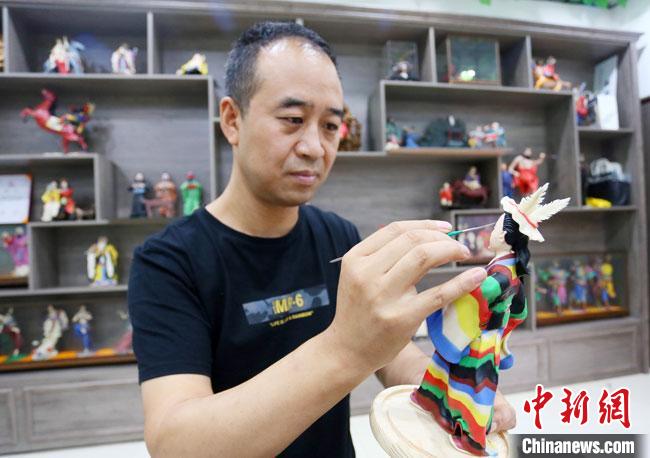 圖為安秋平正在創(chuàng)作代表隴南文縣民俗的《白馬人》作品?！「哒?攝