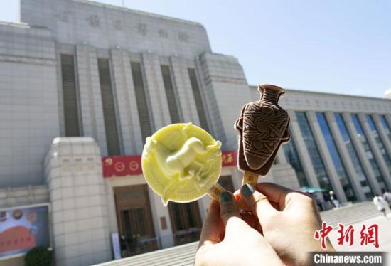 2021年7月30日，游客手拿“銅奔馬”“彩陶瓶”造型的雪糕，在甘肅省博物館前拍照打卡。　高展 攝