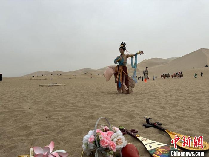 圖為2023年4月底，敦煌大漠“逐舞者”奧楠在鳴沙山月牙泉景區(qū)視頻直播敦煌舞?！●T志軍 攝