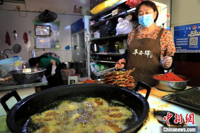 圖為平安驛·河湟民俗文化體驗(yàn)地內(nèi)的商戶炸干板魚?！⊙Φ?攝