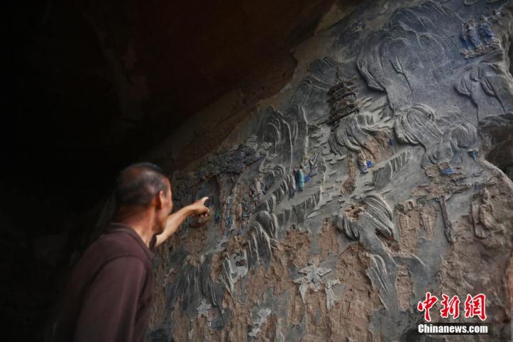 7月15日，甘肅省平?jīng)鍪袥艽h百里石窟長廊羅漢洞石窟內(nèi)，該窟文保員郭建平介紹窟內(nèi)石刻彩繪壁畫。郭建平家中三代人曾自發(fā)保護(hù)羅漢洞石窟。羅漢洞石窟遺存40余個窟龕，以北魏至清代風(fēng)格為主。中新社記者 李亞龍 攝