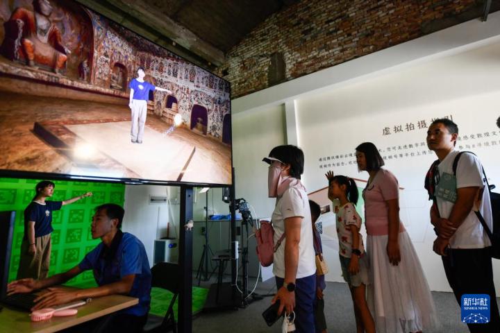 7月22日，游客體驗(yàn)“尋境敦煌——數(shù)字敦煌沉浸展”后，在虛擬演播廳拍攝一段真人與洞窟虛擬場(chǎng)景交互的視頻。新華社記者 郎兵兵 攝</p>
<p>