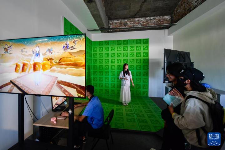 7月22日，游客體驗(yàn)“尋境敦煌——數(shù)字敦煌沉浸展”后，在虛擬演播廳拍攝一段真人與洞窟虛擬場(chǎng)景交互的視頻。新華社記者 郎兵兵 攝</p>
<p>